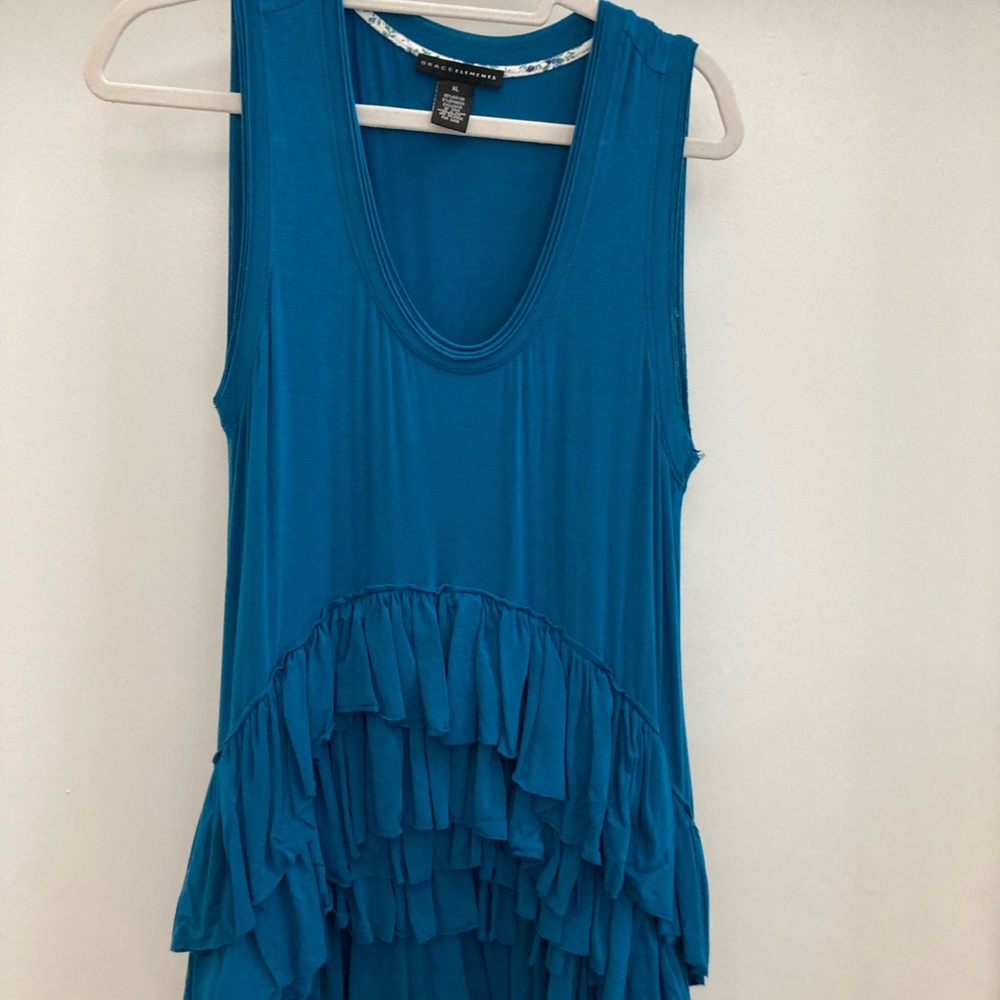 Peacock colored shirt with ruffled bottom.